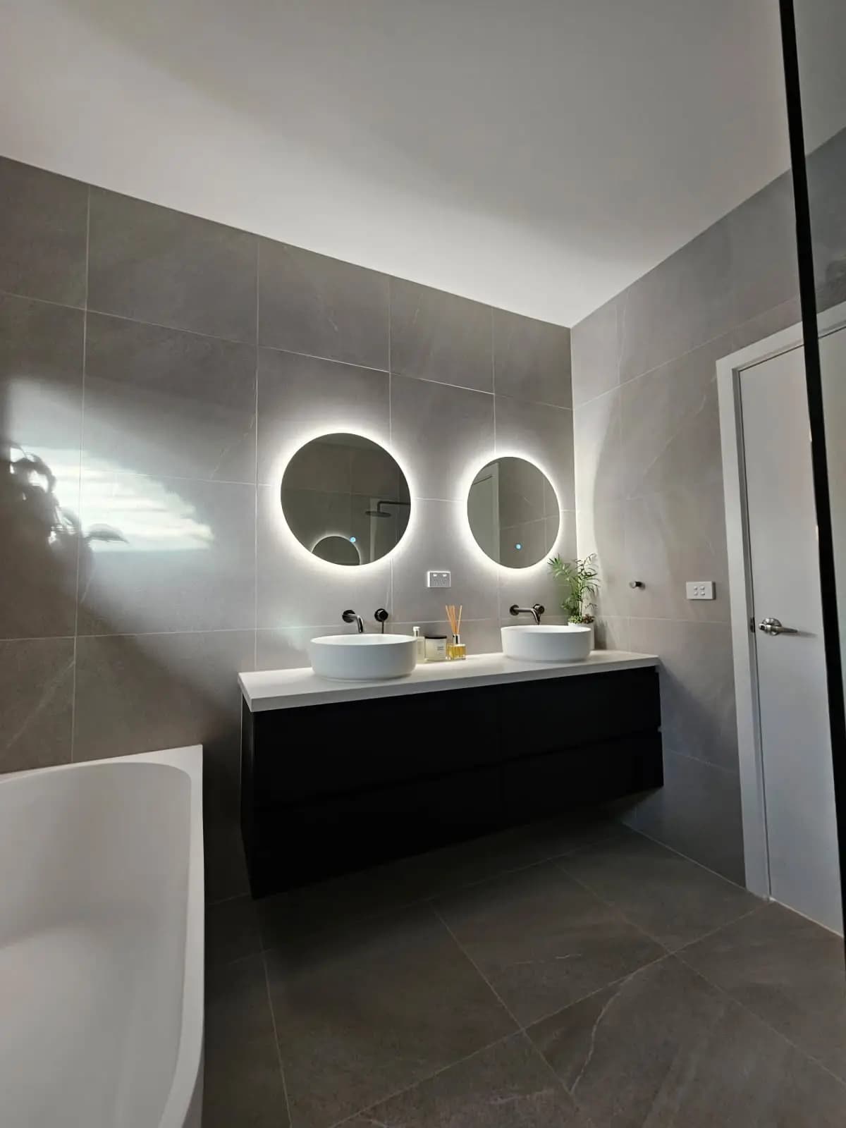 Contemporary kitchen renovation featuring dark cabinetry and stone benchtops in Melbourne